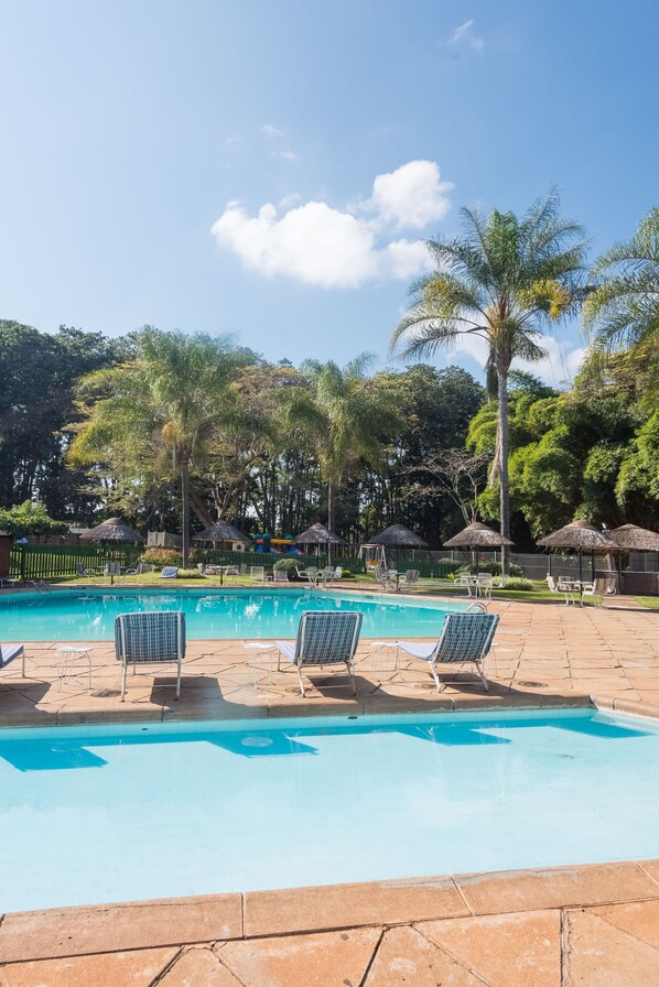 Una piscina al aire libre, sombrillas, sillones reclinables de piscina