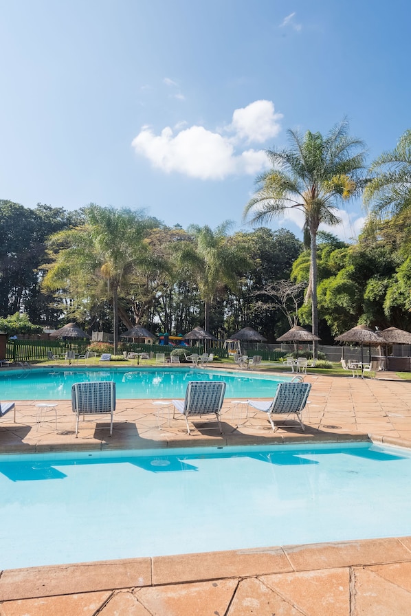 Una piscina al aire libre, sombrillas, tumbonas