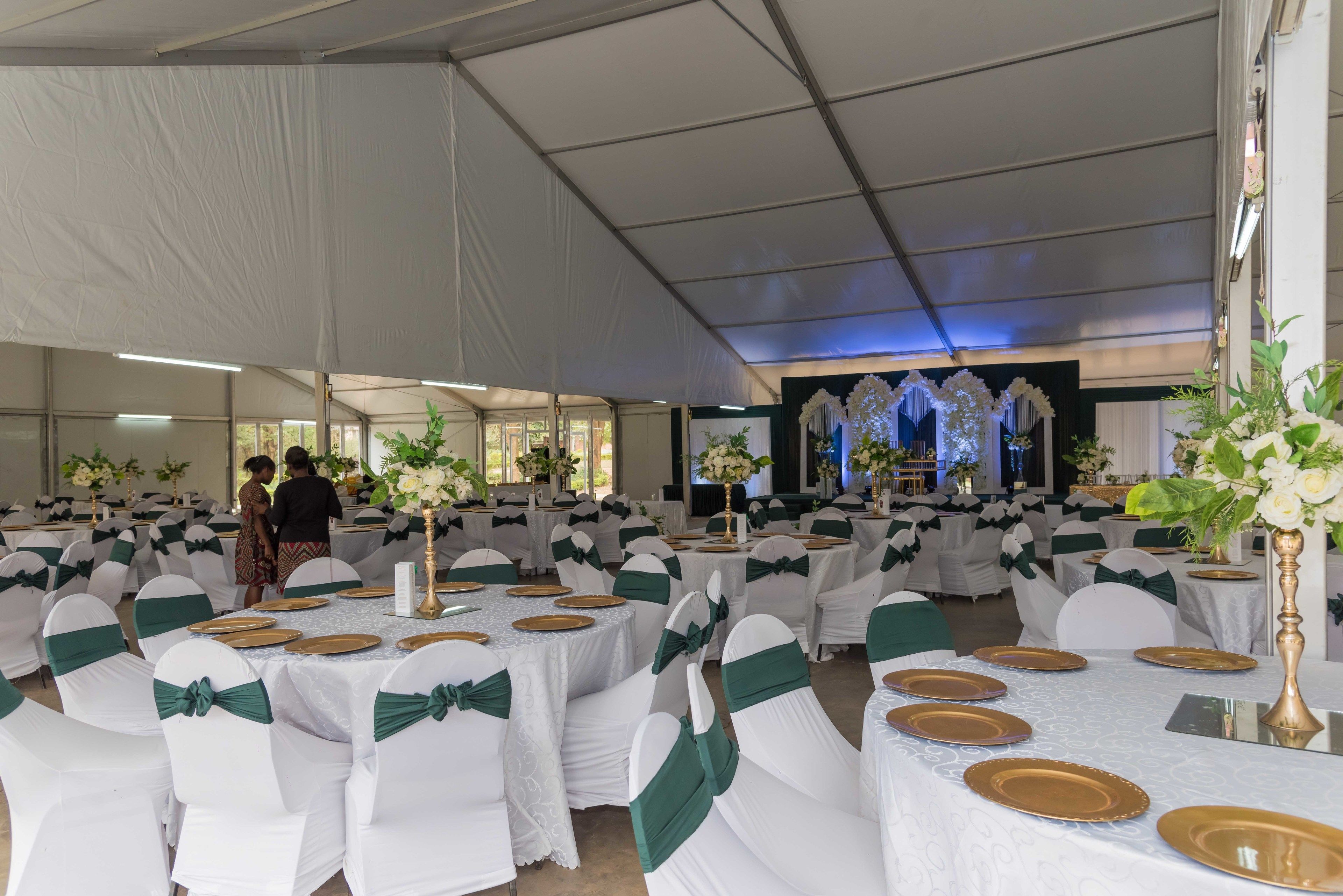 Un salón de banquetes con mesas redondas dispuestas para un evento formal, con manteles blancos y detalles dorados.