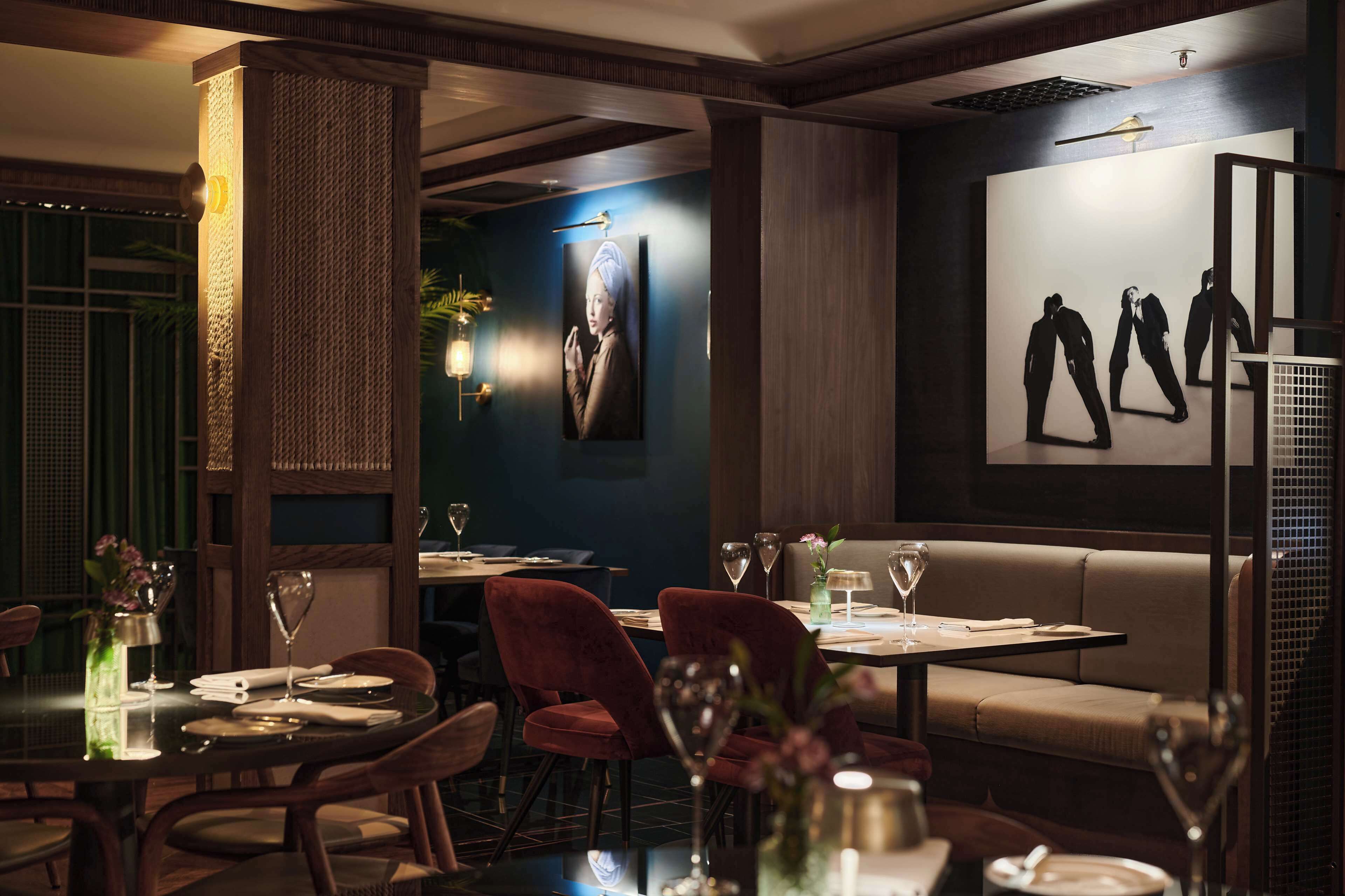 Un interior de restaurante con mesas, sillas y una obra de arte colgada en la pared.