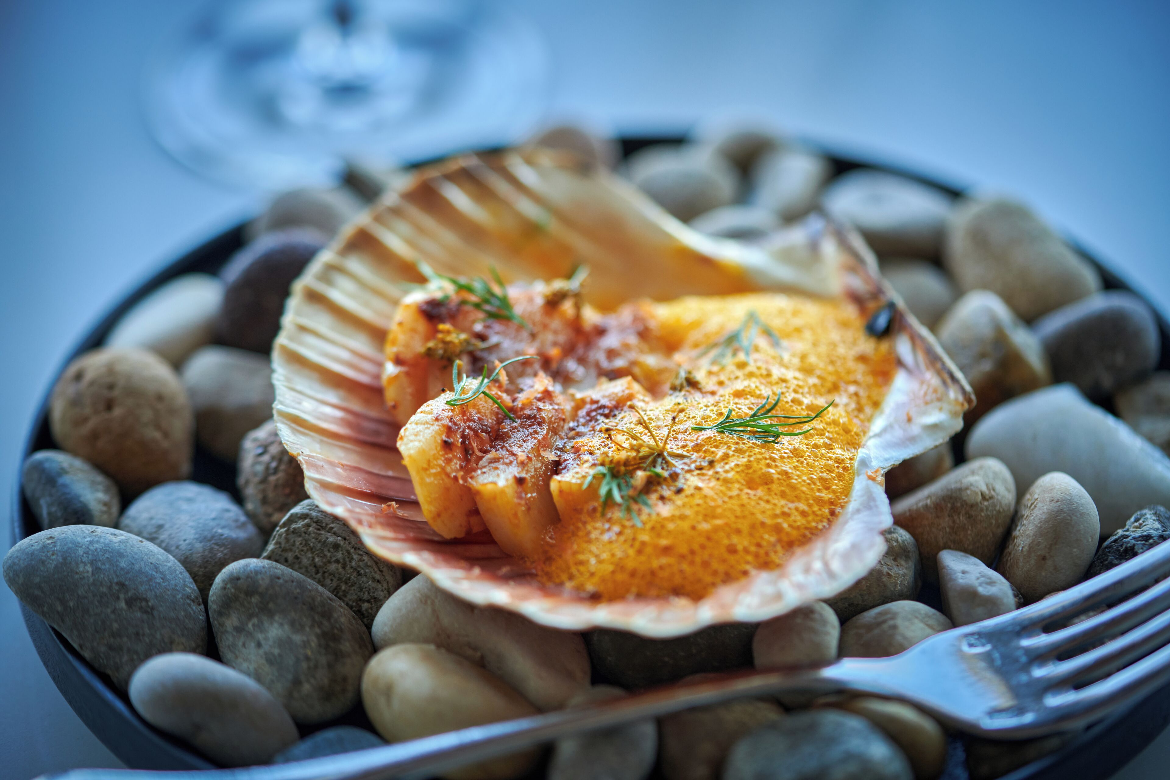 A dish of food served on a shell with a fork on the side.