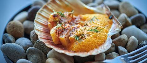 A dish of food served on a shell with a fork on the side.