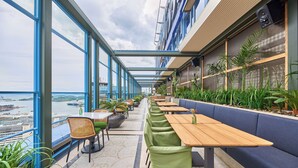 A balcony with tables and chairs, overlooking a body of water with boats. - Radisson Blu Plaza Hotel, Oslo (Oslo)