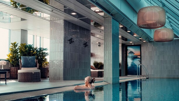 A modern indoor swimming pool with clear blue water, surrounded by lounge areas with seating and plants. - Radisson Blu Plaza Hotel, Oslo (Oslo)