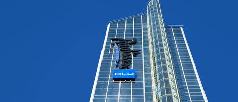 Un edificio alto y moderno de vidrio, con un llamativo letrero 'BLU'.