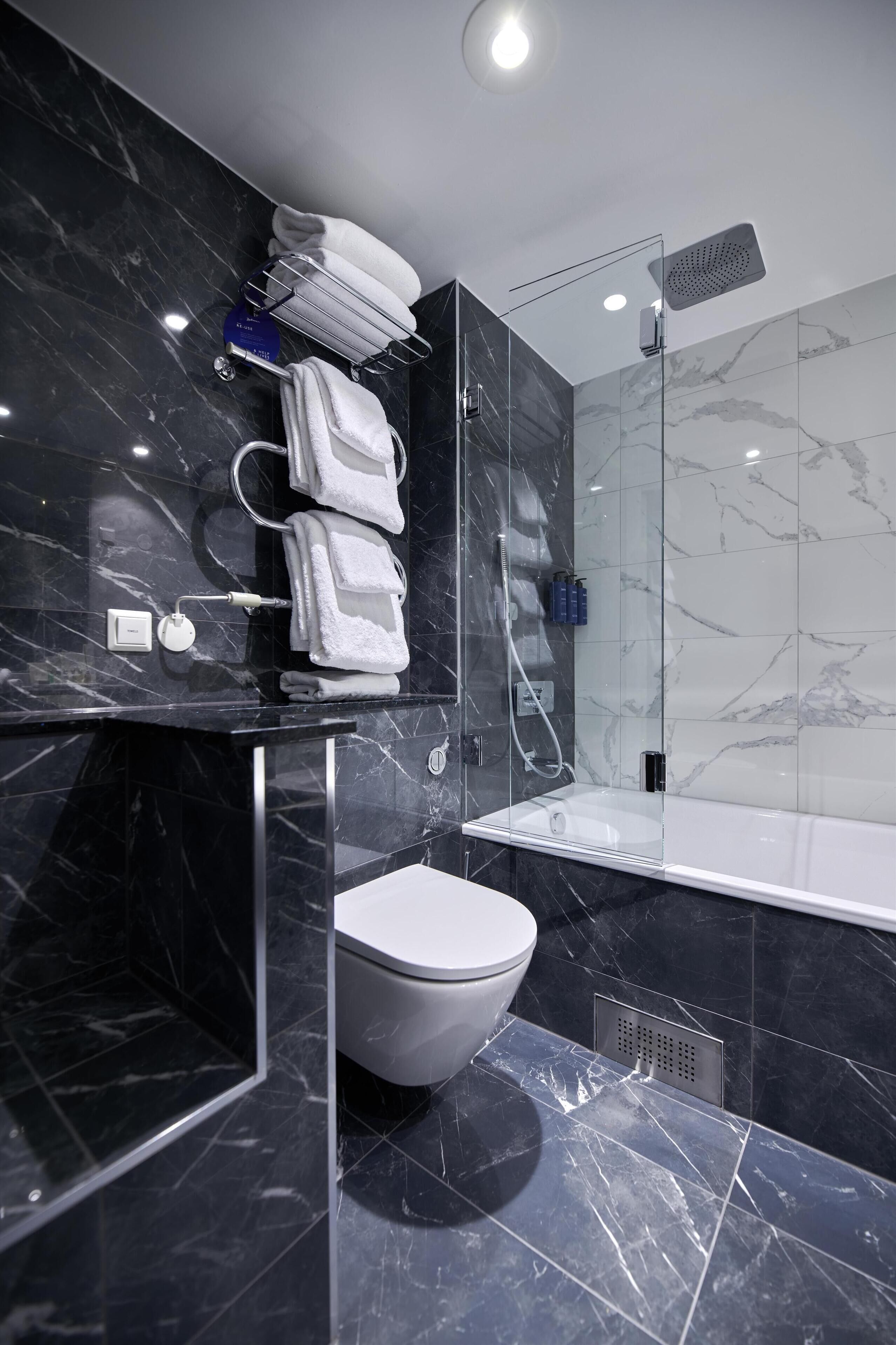 A modern bathroom with a glass-enclosed shower, a toilet, and a sink.