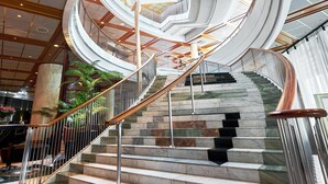 A modern interior with a spiral staircase, marble steps, and a high ceiling with geometric patterns. - Radisson Blu Plaza Hotel, Oslo (Oslo)