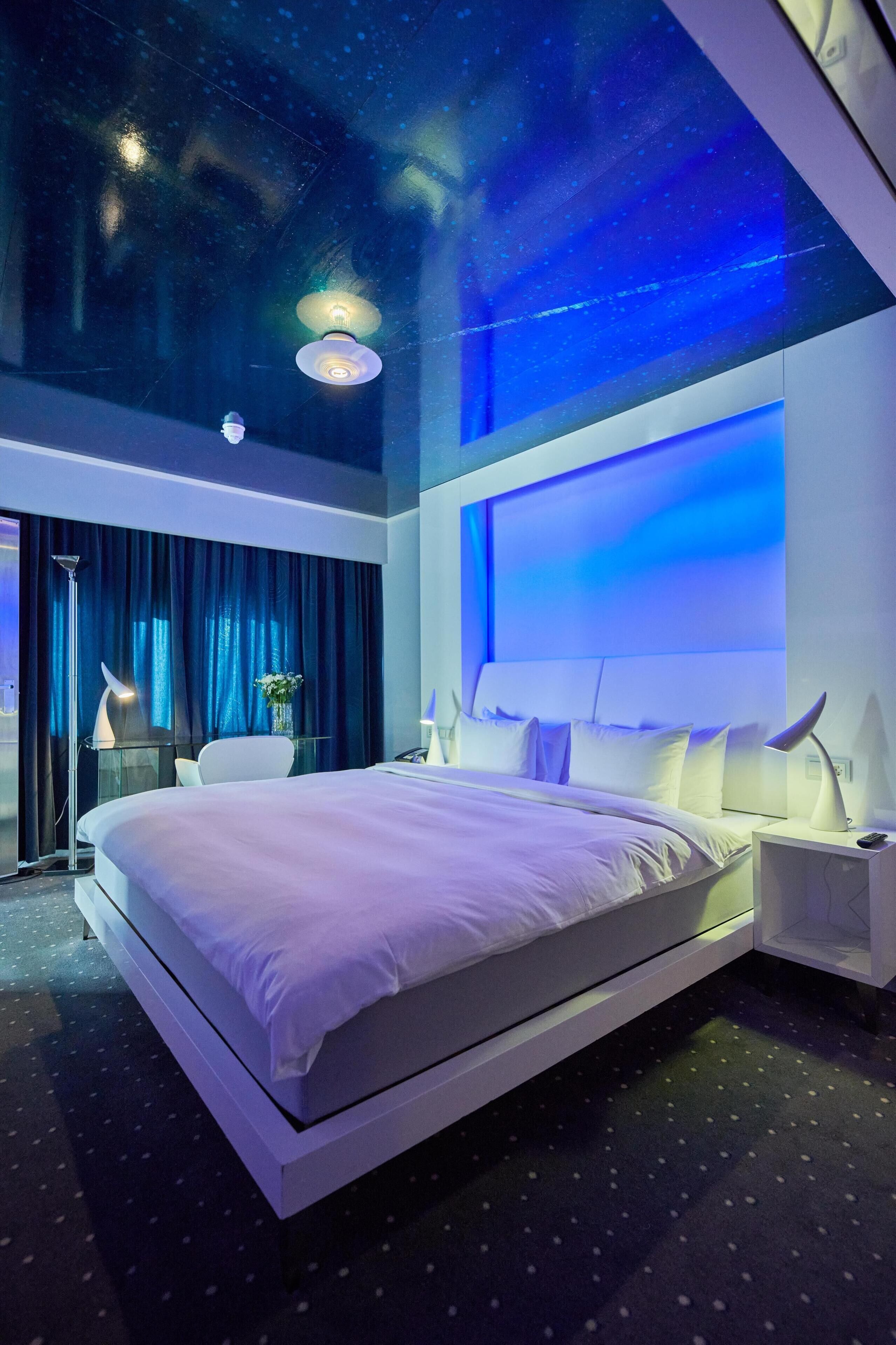 Una habitación de hotel moderna con una cama grande, un escritorio y una mesita de noche.