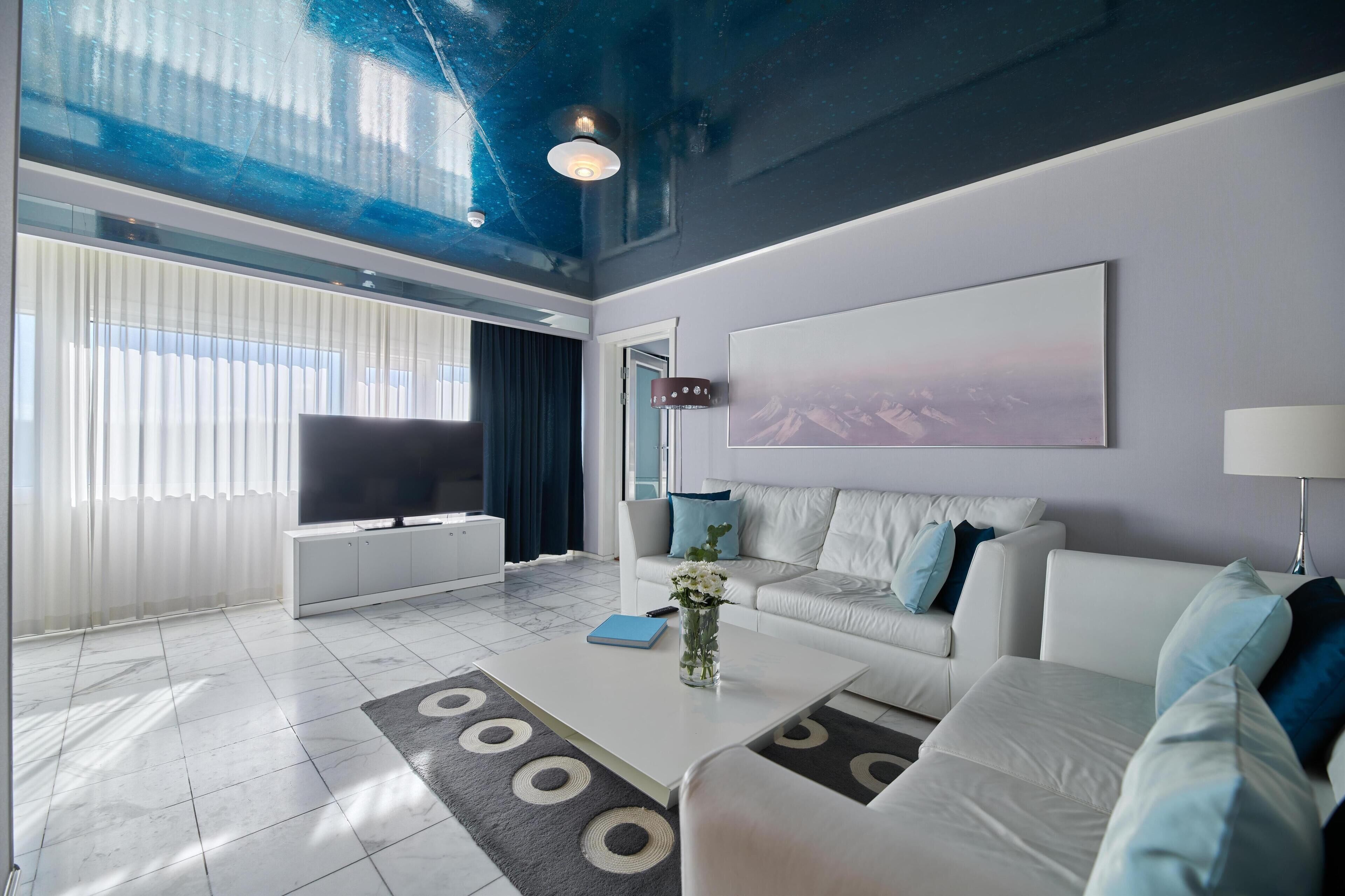 A modern living room with a white sofa, a coffee table, and a large window.