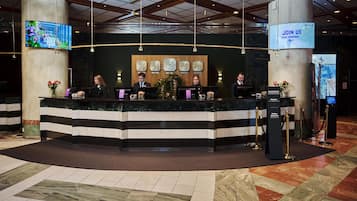 A reception desk with four staff members, a large digital screen, and a 'Join Us' sign.
