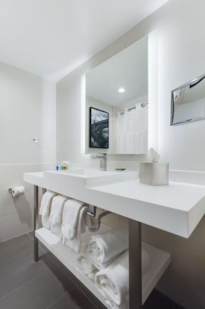 Bathroom features a large mirror, two sinks, and a shelf for towels.