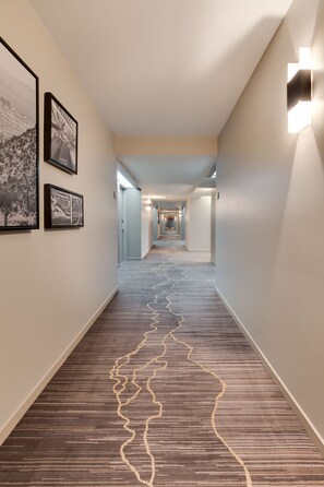 Stroll down the corridor lined with framed artwork and patterned carpet, leading to a series of doors.