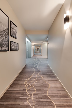 Stroll down the corridor lined with framed artwork and patterned carpet, leading to a series of doors.