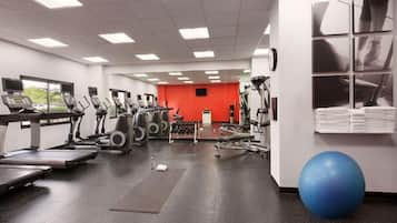 A gym with treadmills, elliptical machines, and a blue exercise ball.