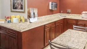 A kitchen with wooden cabinets, a granite countertop, and a dining table.