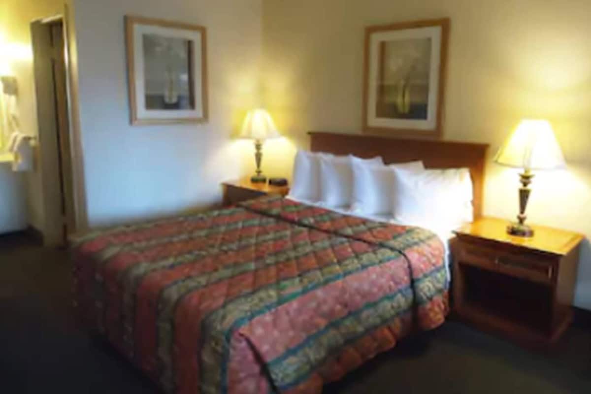 A hotel room with a bed, two bedside tables with lamps, and two framed pictures on the wall.