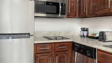 A kitchen with stainless steel appliances, wooden cabinets, granite countertops, and a dishwasher.