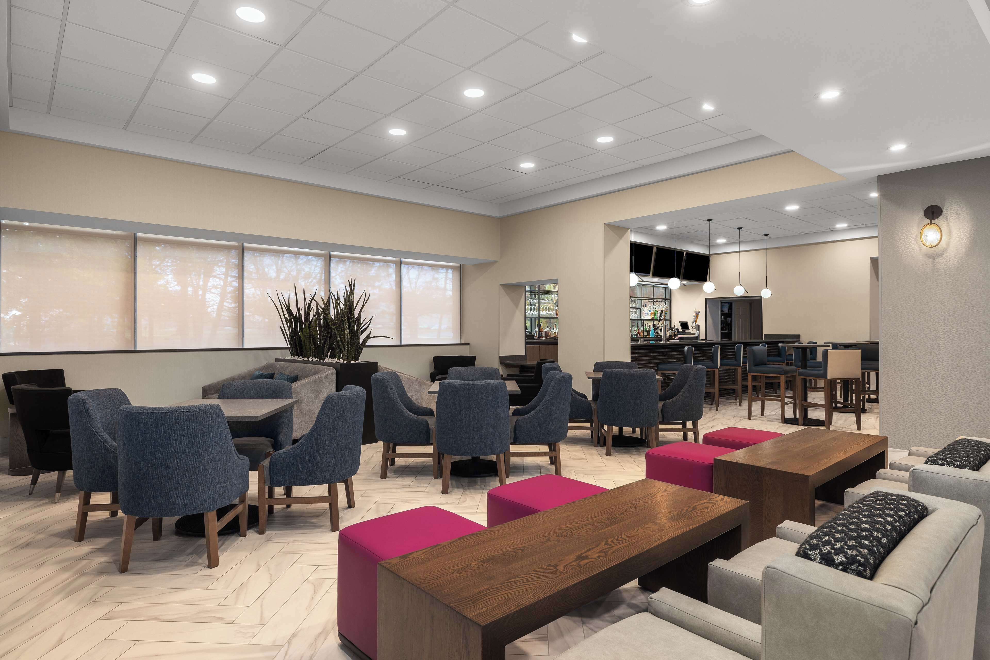 A modern lounge area with seating arrangements, a bar, and a television screen.