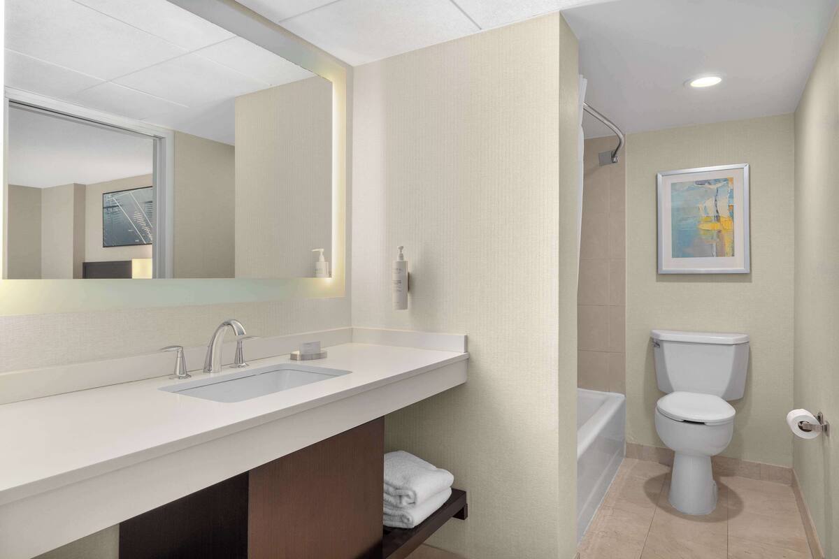 A modern bathroom with a white sink, two faucets, a toilet, and a bathtub.