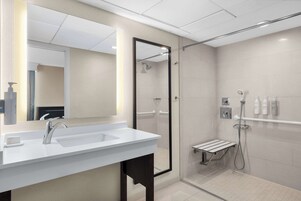 Uma casa de banho moderna com um espelho grande, duas pias, um chuveiro com porta de vidro e um porta-toalhas.