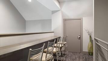 Un salón de conferencias con una larga mesa, sillas, una puerta y un jarrón con flores.