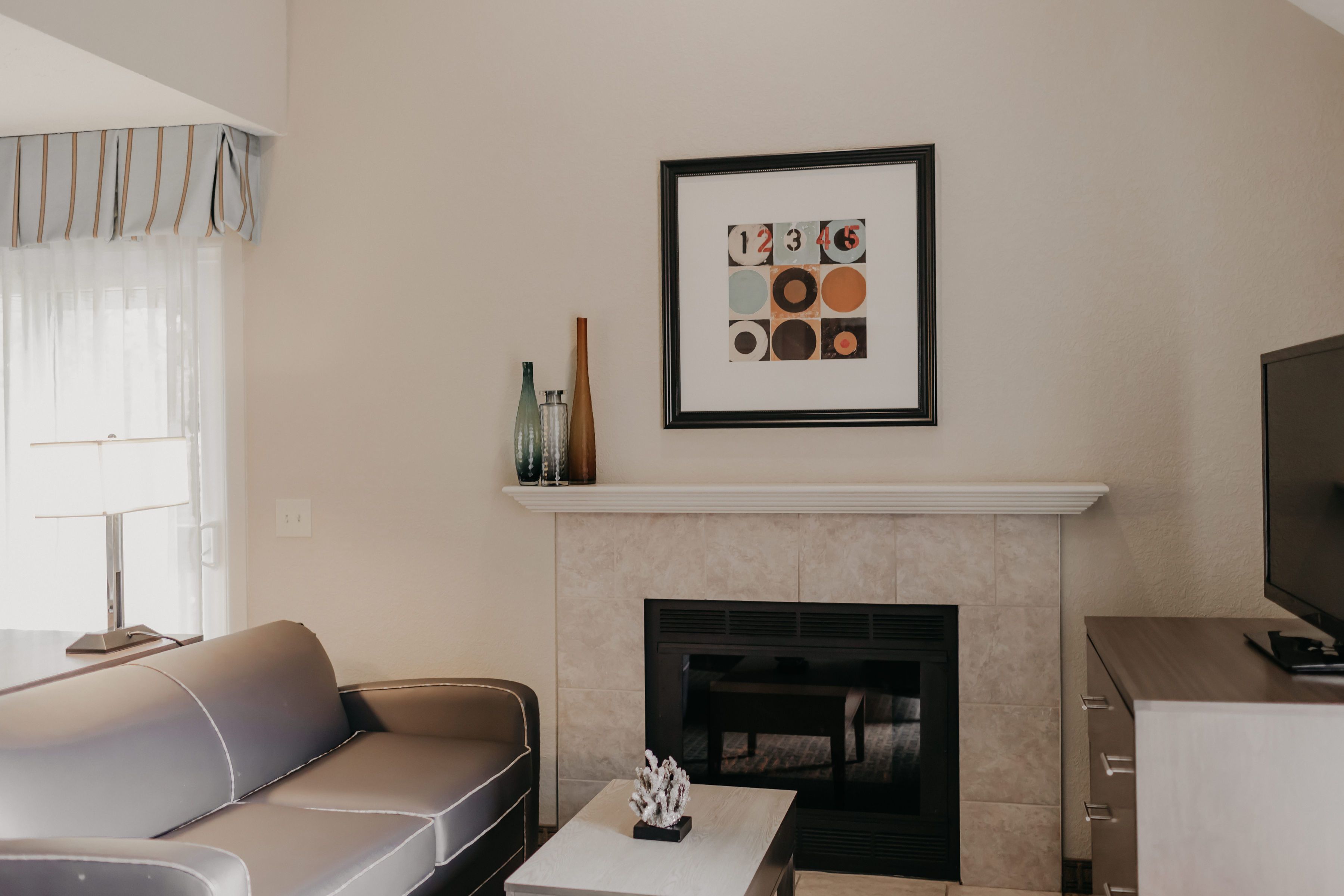 A modern living room with a sofa, a fireplace, and a framed artwork on the wall.