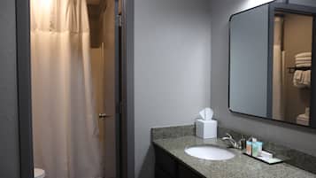 Un baño con cortina de ducha, lavamanos, espejo y toallero.