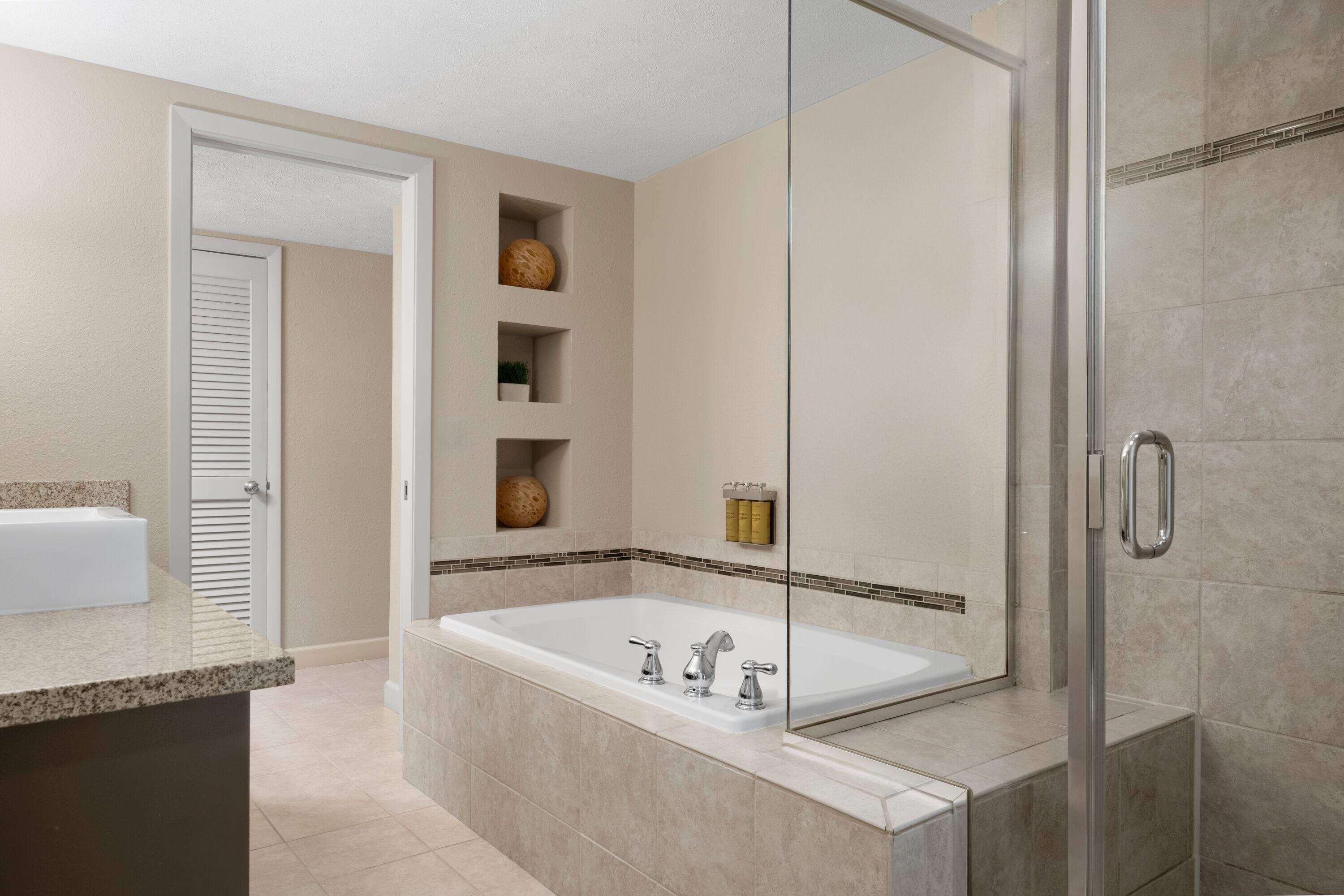 A modern bathroom with a large bathtub, a glass shower enclosure, and a vanity with a sink.