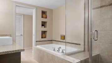Un baño moderno con una bañera grande, cabina de ducha con mampara de vidrio y tocador con lavamanos.