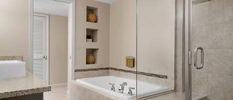 A modern bathroom with a large bathtub, a glass shower enclosure, and a vanity with a sink.