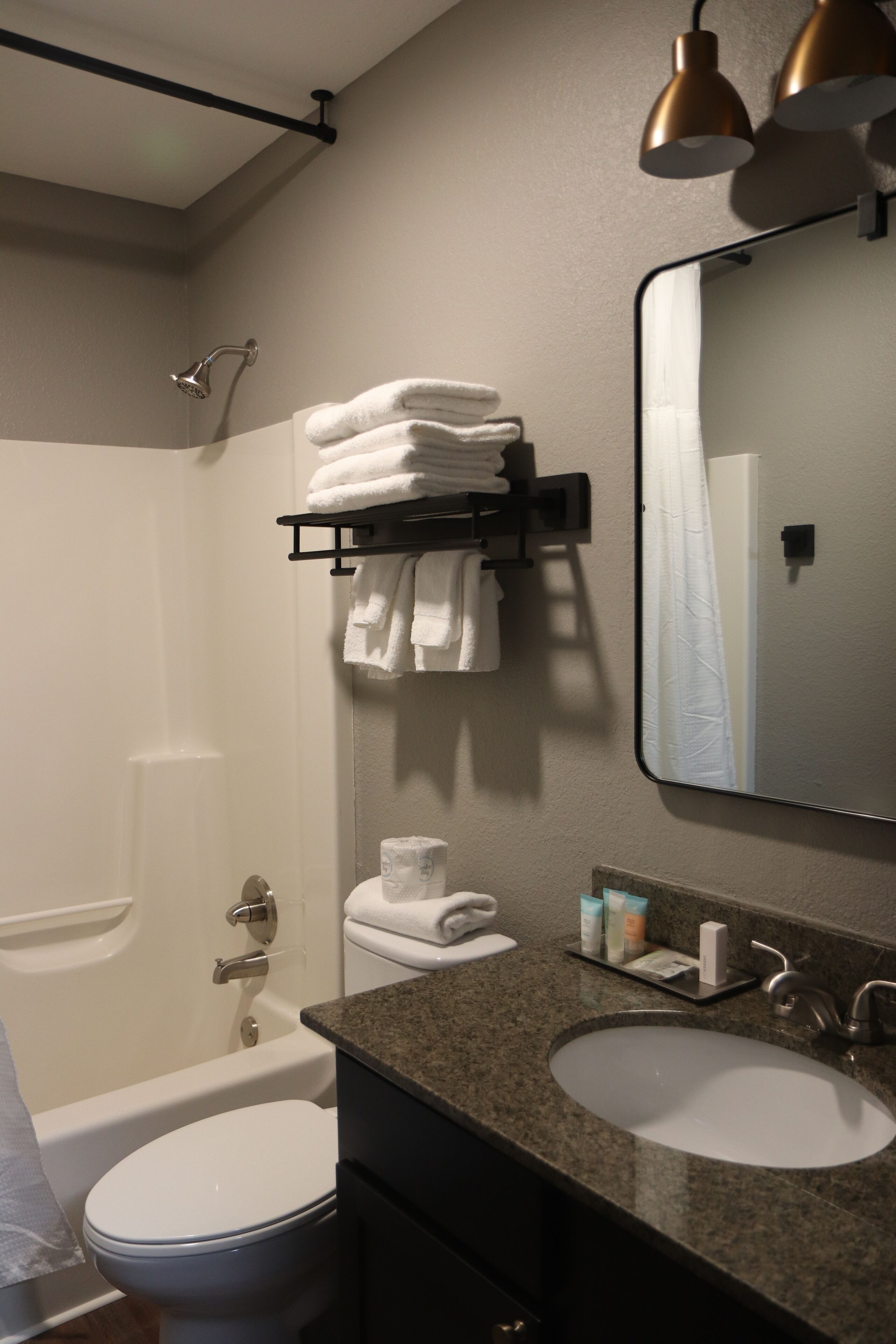 A bathroom with a bathtub, toilet, and two sinks. There are towels on a rack and a mirror above the sink.