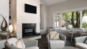 A modern living room with a fireplace, comfortable seating, and a view of the outdoors.