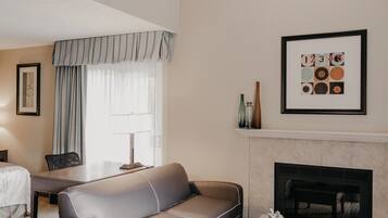 Habitación de hotel con sofá, mesa de comedor, chimenea y un cuadro enmarcado en la pared.