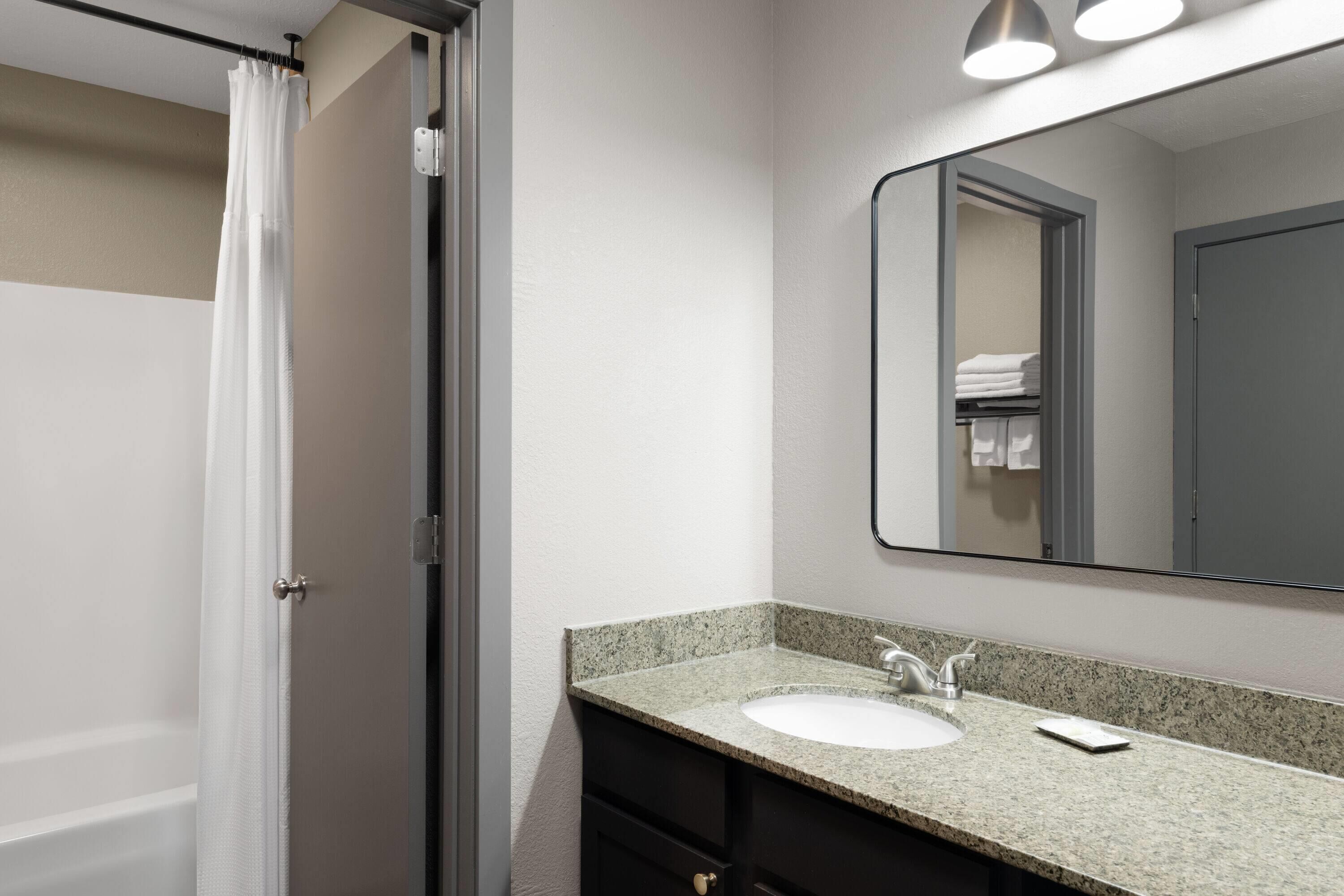 A bathroom with a shower, a sink, and a mirror.