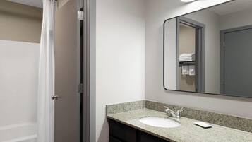 A bathroom with a shower, a sink, and a mirror.