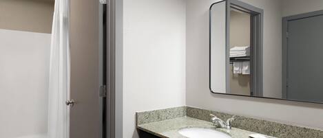 A bathroom with a shower, a sink, and a mirror.