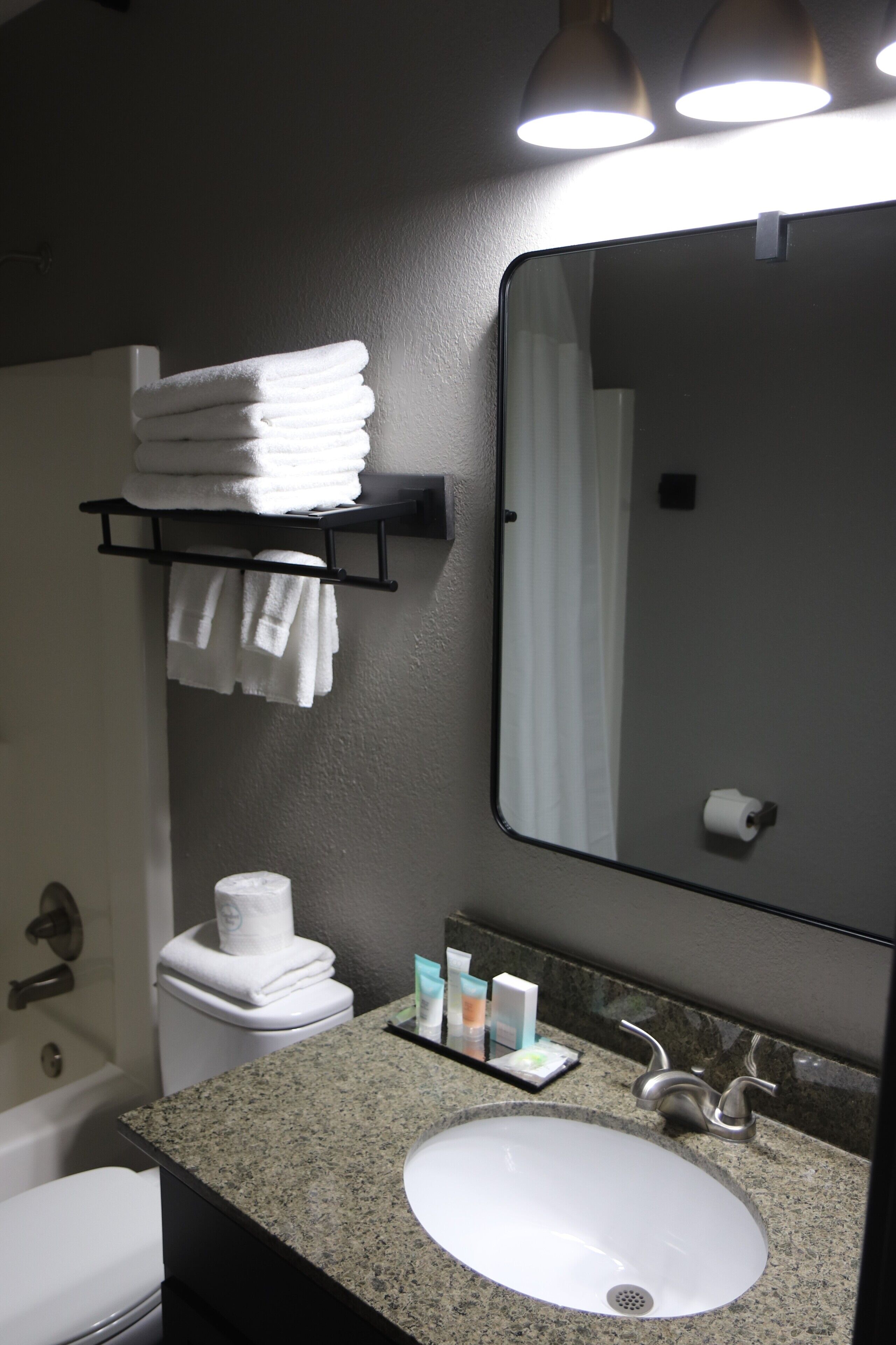 A bathroom with a white sink, a mirror, a towel rack, and a toilet.