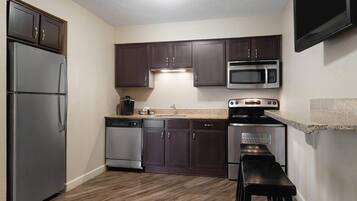 A modern kitchen with dark wooden cabinets, stainless steel appliances, and a granite countertop.