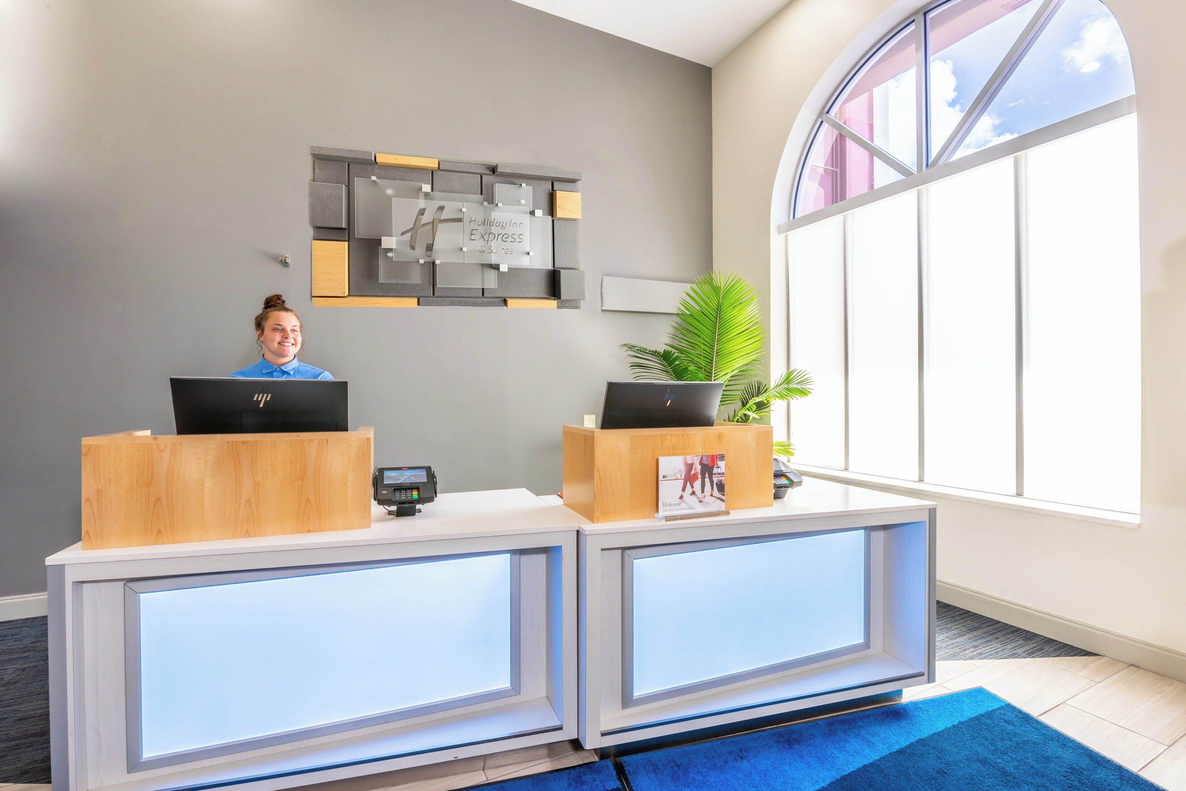 A reception desk with two computer monitors, a digital screen, and a sign for Holiday Inn Express & Suites.