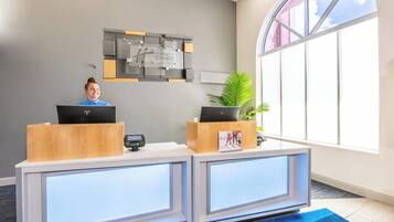 Un comptoir d’accueil équipé de deux écrans d’ordinateur, d’un écran numérique et d’une enseigne indiquant « Holiday Inn Express & Suites ».