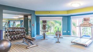 Une salle de sport équipée de tapis de course, d’haltères et d’autres appareils d’exercice.
