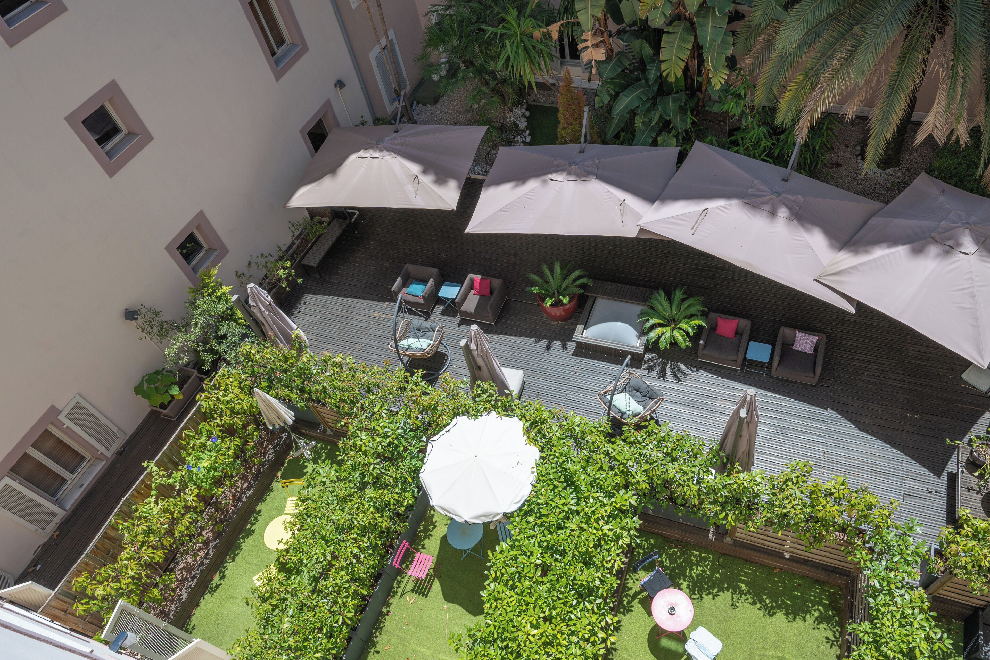 Eine Außenpatio-Terrasse mit verschiedenen Sitzgelegenheiten, Sonnenschirmen und Pflanzkübeln.