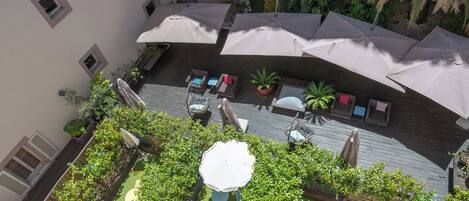 An outdoor patio area with multiple seating arrangements, umbrellas, and potted plants.