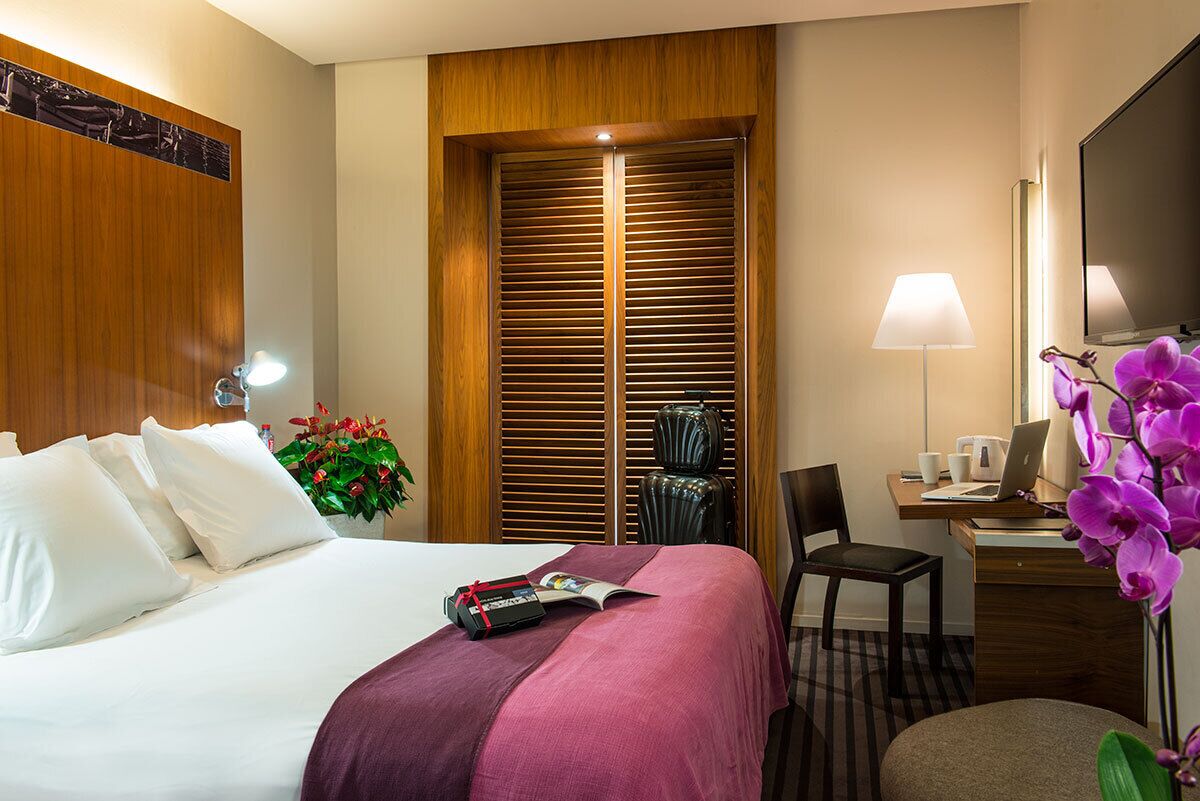 Une chambre d’hôtel comprenant un lit, un bureau, une chaise, une lampe et une armoire.