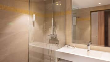 A modern bathroom with a glass-enclosed shower, a white sink, and a mirror reflecting the room.