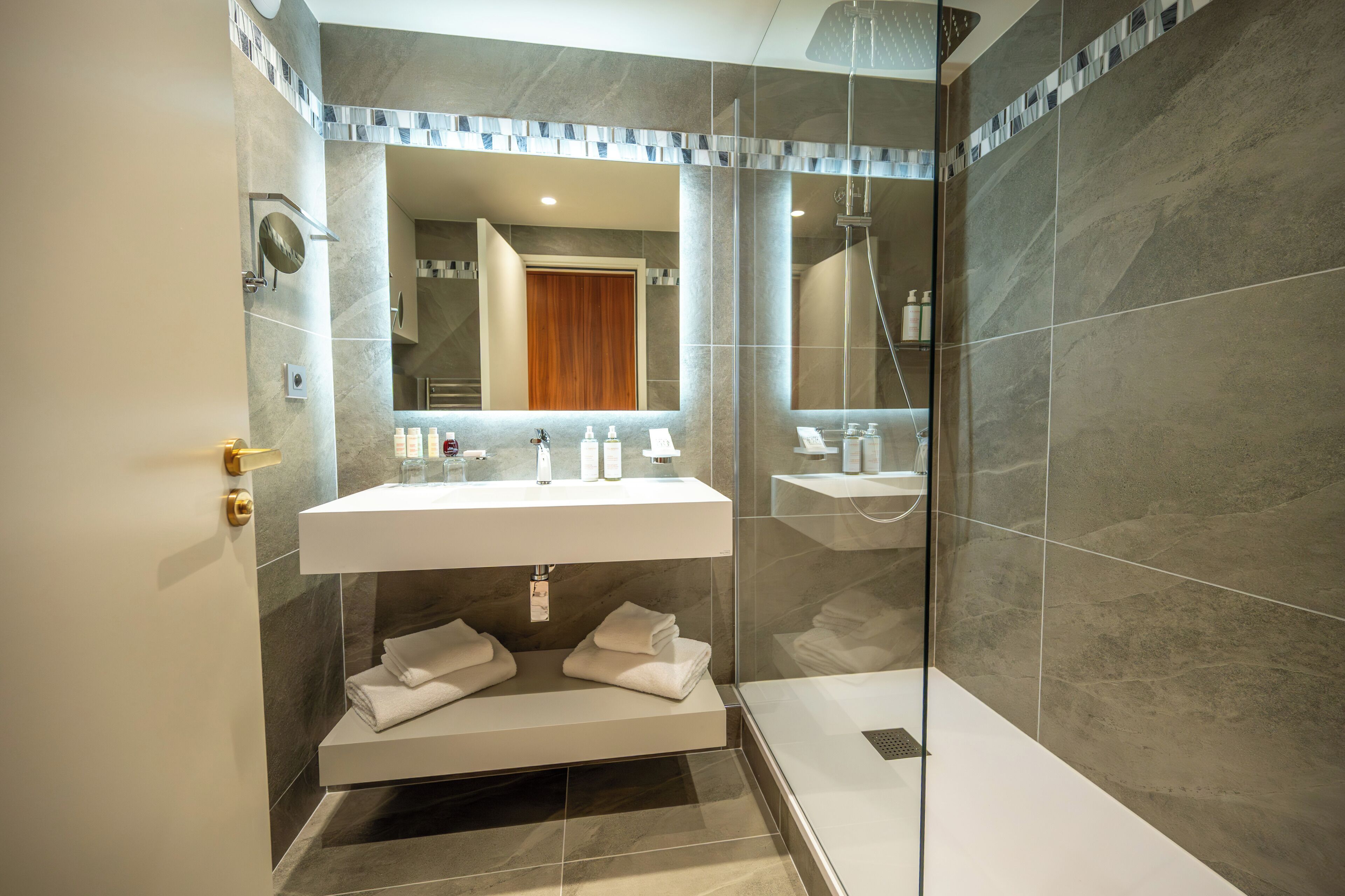Une salle de bain moderne dotée d’une douche à parois de verre, d’un meuble-lavabo à deux vasques et d’un porte-serviettes intégré.