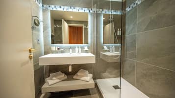 Une salle de bain moderne dotée d’une douche à parois de verre, d’un meuble-lavabo à deux vasques et d’un porte-serviettes intégré.