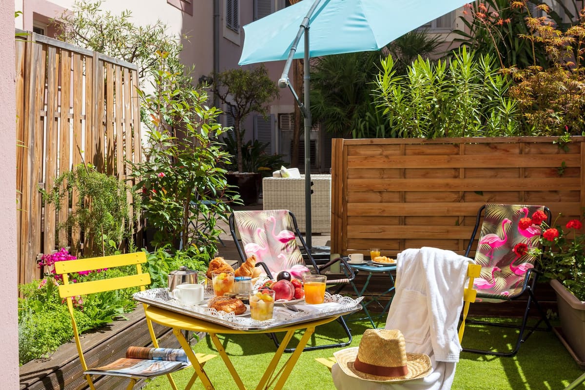 An outdoor patio with a table set for breakfast, surrounded by chairs and a wooden fence.