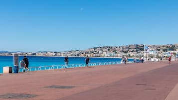 Eine Uferpromenade mit freiem Blick auf das Meer und einer Stadtlandschaft im Hintergrund.