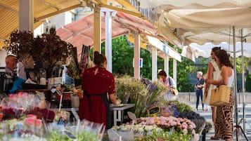 Ein Blumenmarkt mit verschiedenen Blumen und Pflanzen, die unter Sonnenschirmen präsentiert werden.